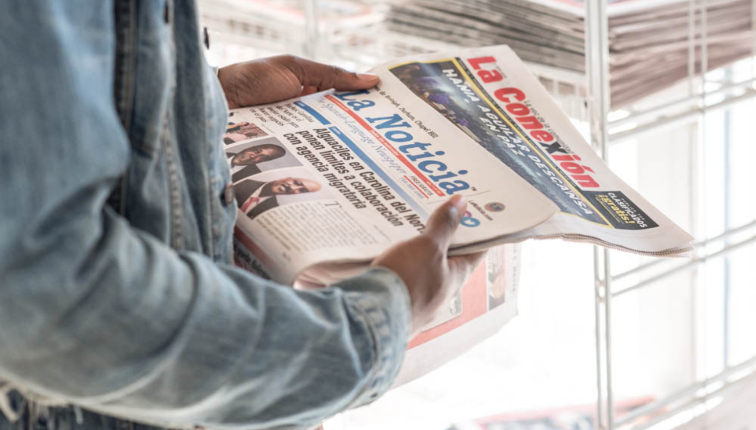 Photo of Spanish-language newspapers, held by a reader.
